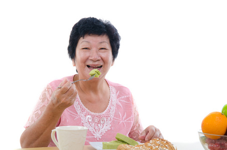 中国高级女性吃与孤立的白色背景