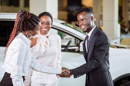顾客在汽车经销处买车。女人和男人握手