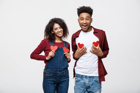 非洲裔美国人欢快的夫妇持有红纸心的肖像喜欢玩站在灰色背景