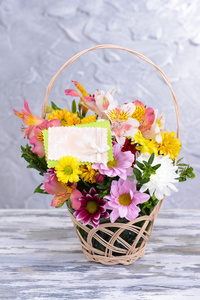 鲜艳的花朵，在灰色的背景上表格的柳条篮子里的美丽花束