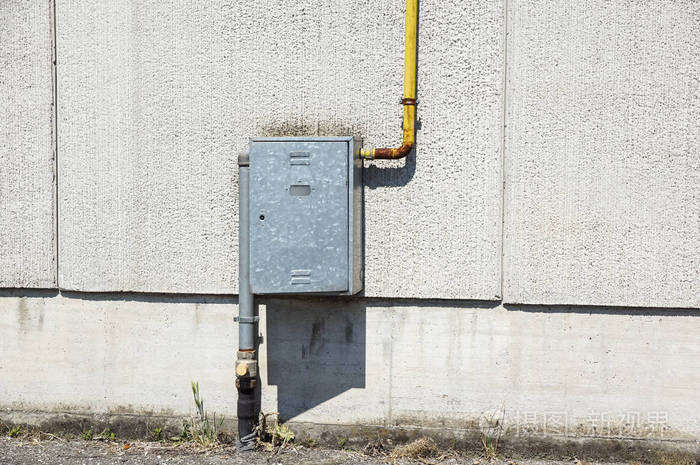 用金属盒装水表的石膏墙前固定有支架的旧水金属管