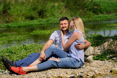 爱夫妇坐在岩石在河和日落看法