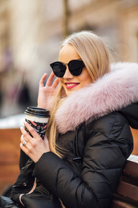 漂亮女孩戴墨镜, 在街上喝咖啡。