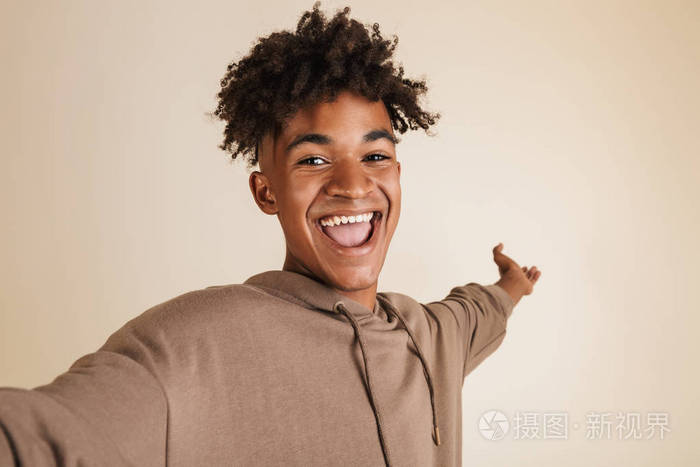 一个开朗的年轻美国黑人男子的肖像穿着帽衫采取自拍隔离