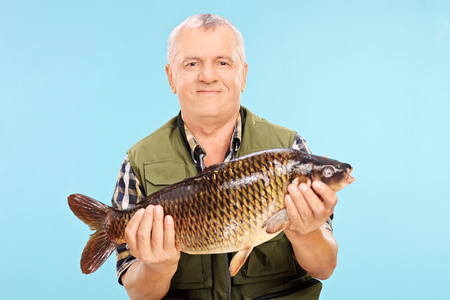 成熟的渔民拿着淡水鱼照片