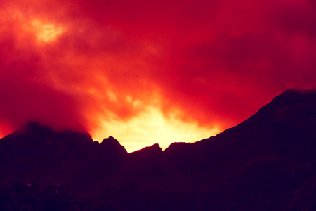 山顶上勾勒出多云的日落天空。烧毁了红色日落。美丽的自然挪威。罗弗敦群岛。瑞尼