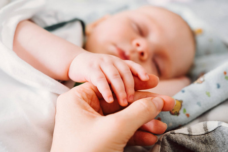 可爱的新生儿抱着妈妈的手睡觉。幸福家庭理念