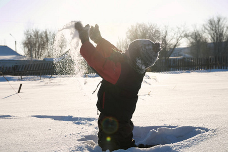 男孩吹散雪在空气中, 户外儿童活动在冬天寒冷, 愉快的童年有乐趣