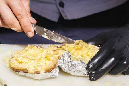 库克用刀子将馅料用奶酪涂在烤柑桔的箔上。特写