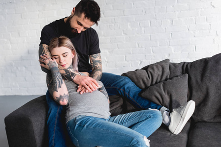 男的纹猫纹身男友抱着怀孕的女朋友在沙发上在家照片