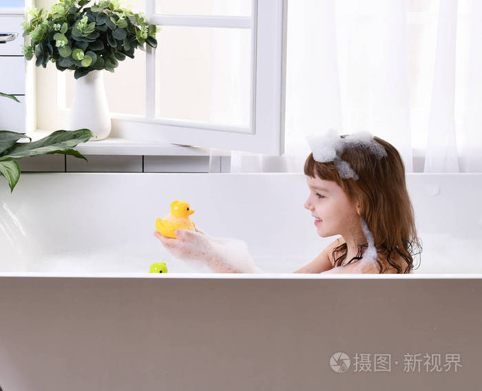 快乐的小女孩孩子坐在浴缸里的浴室