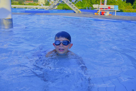 可爱的小男孩在游泳池夏天的一天。夏日快乐的童年概念。在明亮的蓝色水中复制空间