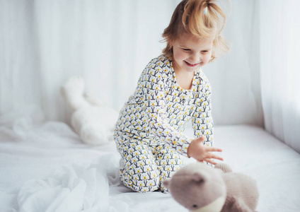 孩子在柔软的温暖的睡衣在床上玩耍