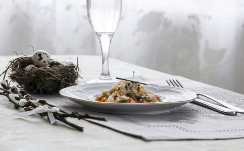 餐桌上的餐巾菜蔬菜炖绿洋葱玻璃叉刀和枝鹌鹑蛋盐胡椒