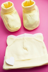 婴儿黄色的赃物。儿童鞋和玩具的粉红色背景。新生儿。顶部视图
