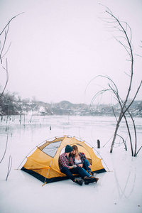 年轻夫妇坐在帐篷里, 冬季徒步旅行雪背景