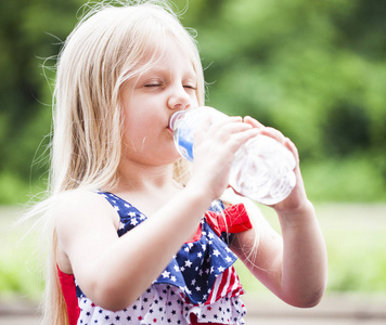 可爱的小女孩的画像在户外饮水照片
