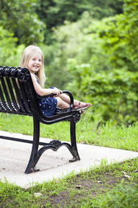 坐在公园长椅上的快乐小女孩肖像