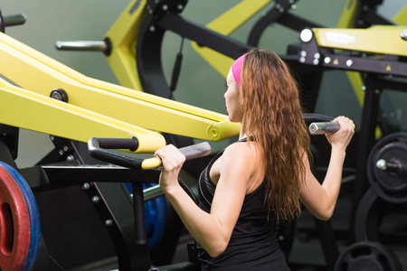 运动, 健身, 生活方式和人的概念美丽的女人在健身机上伸缩肌肉