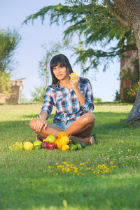 美丽的女人，在绿色的草地上吃水果