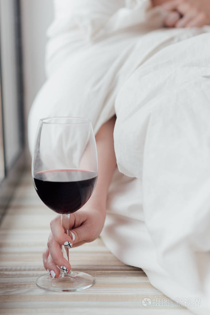 女性手捧着大酒杯半满酒女人坐在一个大窗户旁边指甲艺术