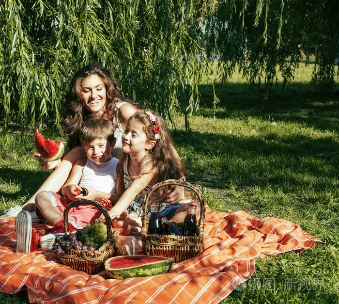 可爱的幸福的家庭野餐铺上绿草的母亲和孩子