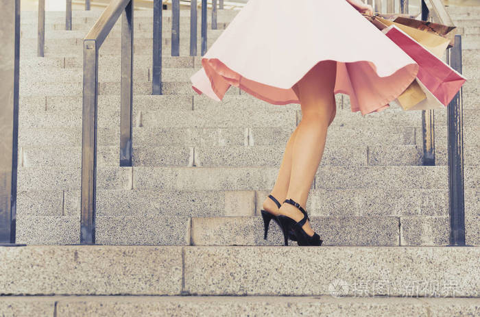 穿着裙子的女孩在楼梯上用纸包旋转