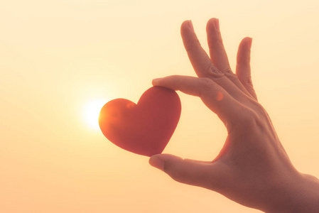 日落时手捧红心的特写和剪影照片