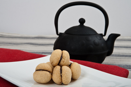 意大利小甜饼称为baci di dama用红布和一个大的黑色茶壶的白板上