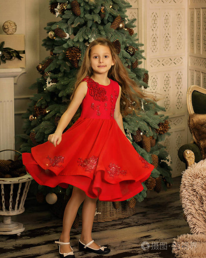 美丽的女孩在圣诞树上微笑着圣诞礼物新年婴孩笑红色礼服