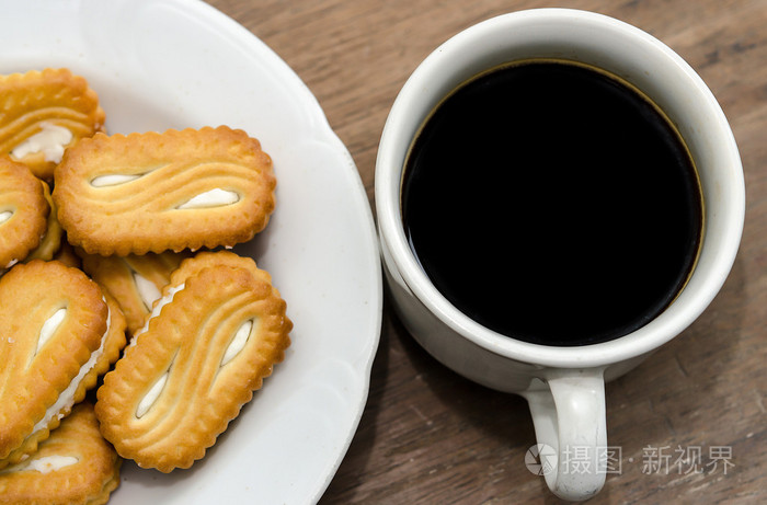 在木桌上的 cookie 的黑咖啡