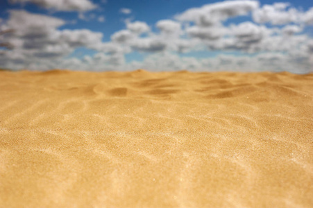 金色的沙子在炎热和阳光明媚的沙漠。黄色的沙子对蓝天与云彩
