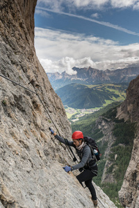 年轻漂亮的女登山者在一个通过 Ferrata 在白云岩巴迪亚