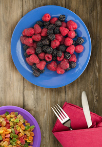 盘子里的黑莓和覆盆子。在木背景的黑莓和覆盆子。素食