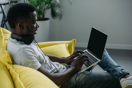 微笑的年轻非洲裔美国人使用笔记本电脑与空白屏幕在家里