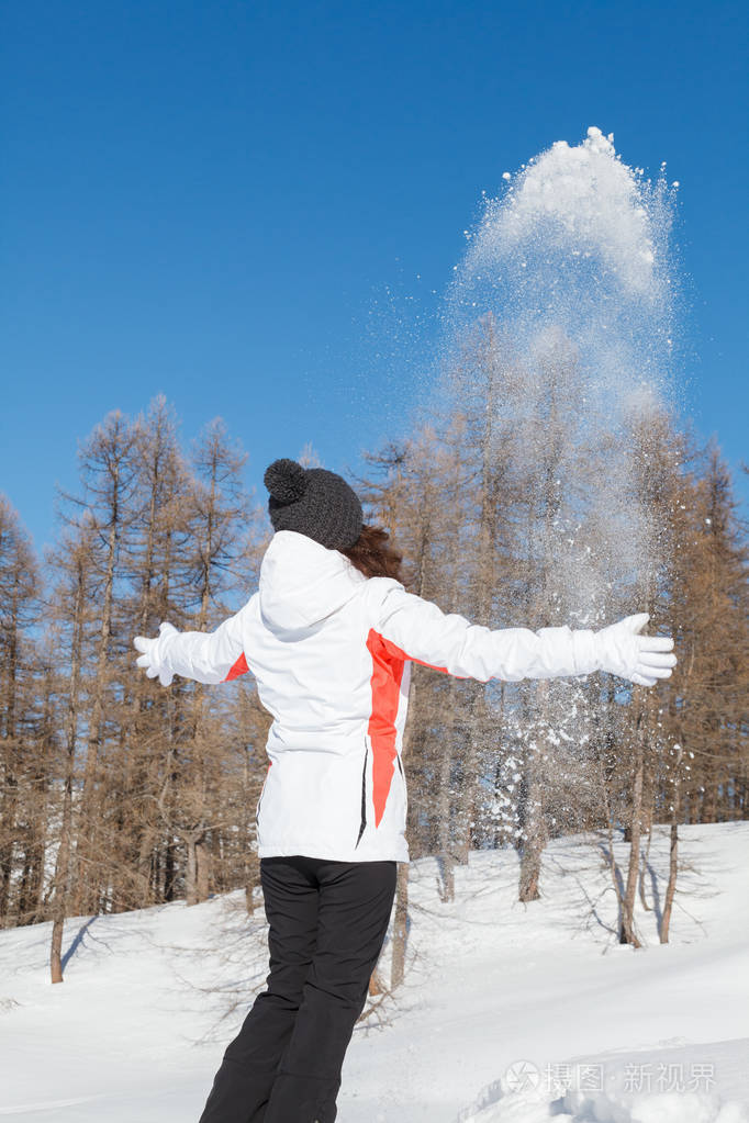 女孩玩雪和户外乐趣在冬季与蓝色滑雪和树木的背景