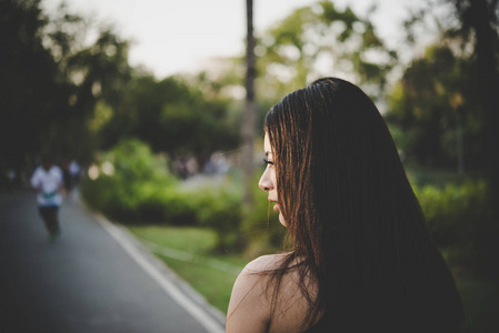 年轻漂亮的女孩是悲伤站在公园里, 她感到失望和孤独