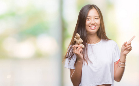 年轻的亚洲妇女持有新鲜的有机在孤立的背景非常高兴地指着手和手指的一侧