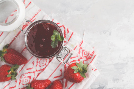 草莓果酱在一个玻璃罐子与浆果, 灰色背景