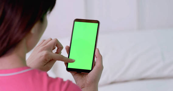 使用绿色屏幕的手机的妇女