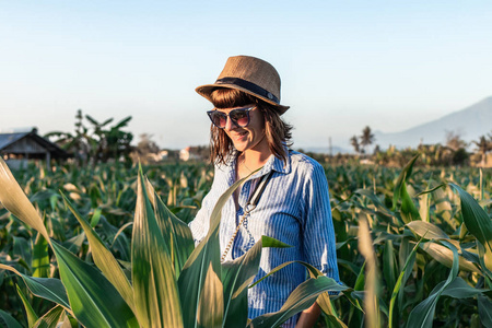 在日落时, 贡的背景下, 玉米田上有草帽的年轻女子旅游旅行者。巴厘岛。芒贡