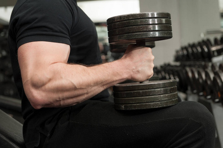 肌肉健美的家伙拿着大黑铁哑铃在健身房.有大手肌肉在健身房锻炼的人.