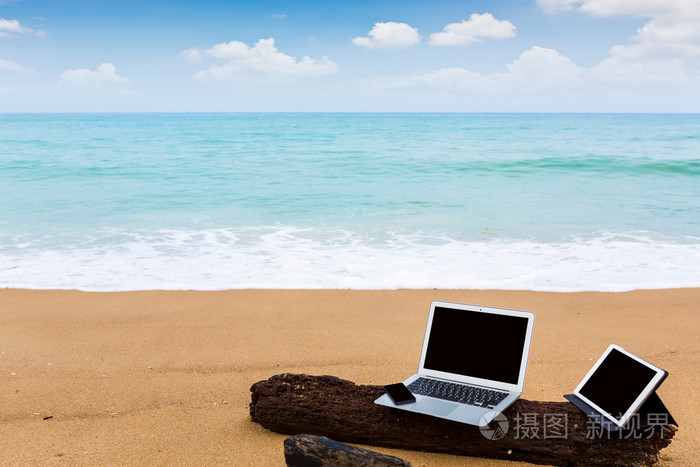 笔记本电脑 平板电脑和智能手机在夏天的时候沙滩上