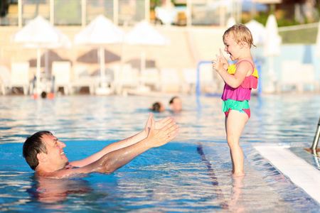父亲和女儿在户外游泳池玩乐