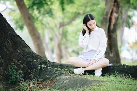 亚洲女孩的肖像与白色衬衫和裙子坐在放松 n 户外自然复古电影风格