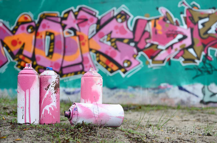 二手油漆罐躺在墙边的地面上, 用粉红色和绿色的颜色画出美丽的涂鸦