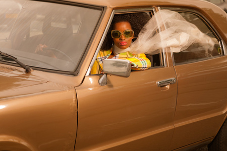 戴墨镜驾驶在布朗的 70 年代复古时尚黑人女子