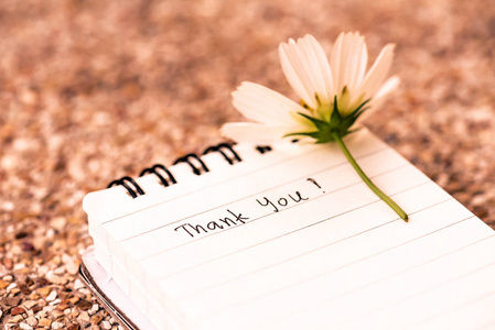 感谢提醒感谢您的文本在白色页笔记书与浪漫白色花在木背景照片