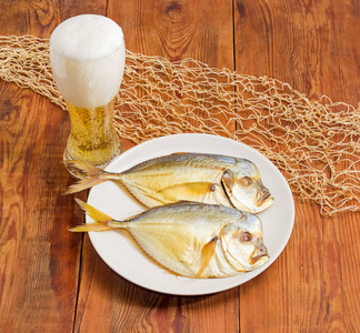 烟熏大西洋翻车鱼在盘子和啤酒在老桌上