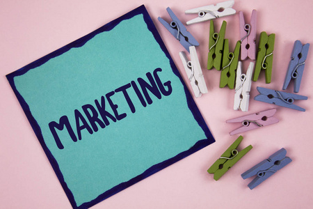 手写文字书写营销。概念意味着广告销售产品从一个公司促销的东西写在纸上的纯粉红色背景木夹子旁边